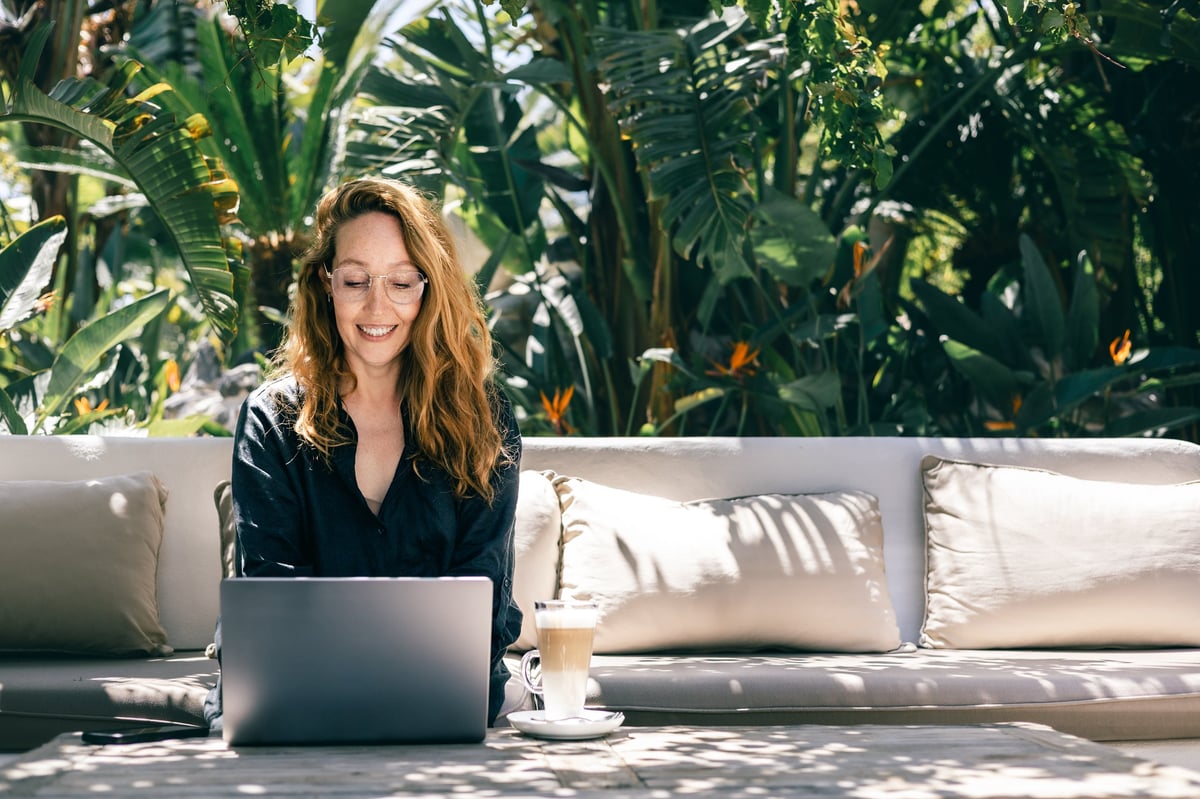 Business owner relaxing in a tropical garden with a laptop, enjoying a peaceful week away